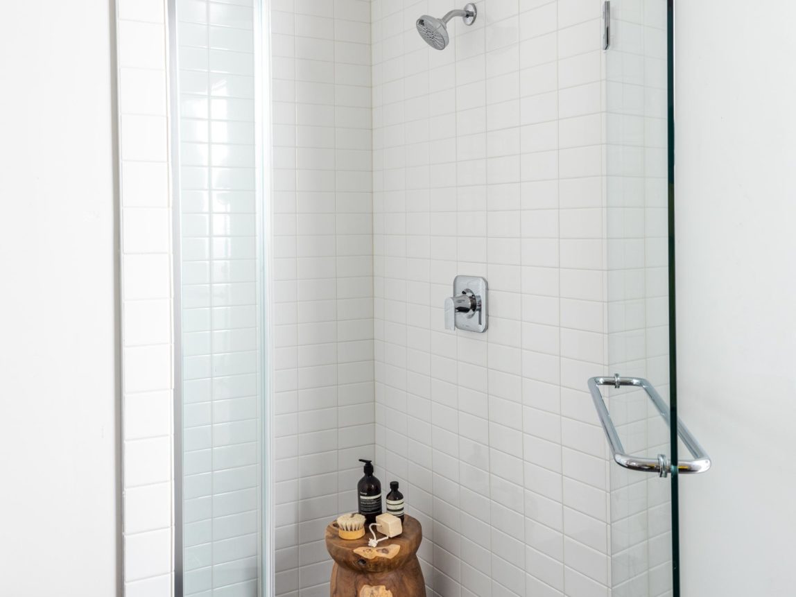 walk-in shower with floor-to-ceiling subway tile and hex floor tile