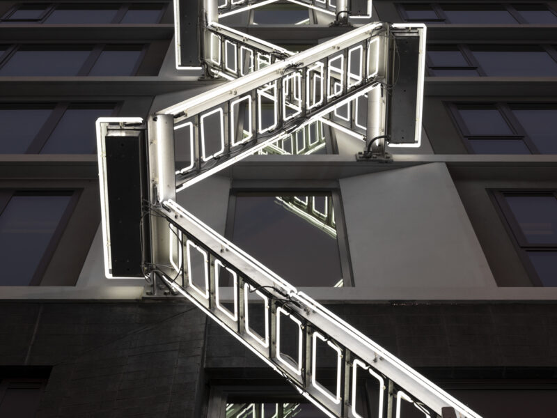 Ladder neon light sculpture on side of 50 Jones