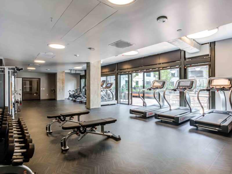 Luxury Apartments in Downtown San Francisco, CA with In-Unit Washer and Dryer - 50 Jones - Fitness Center with Free Weights, Workout Benches, Treadmills, Stationary Bikes, and Floor-to-Ceiling Window Wall.