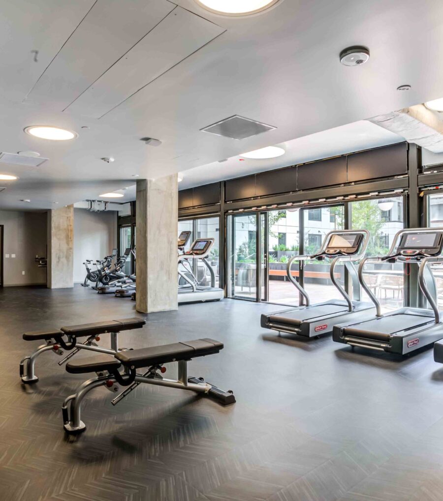 Luxury Apartments in Downtown San Francisco, CA with In-Unit Washer and Dryer - 50 Jones - Fitness Center with Free Weights, Workout Benches, Treadmills, Stationary Bikes, and Floor-to-Ceiling Window Wall.